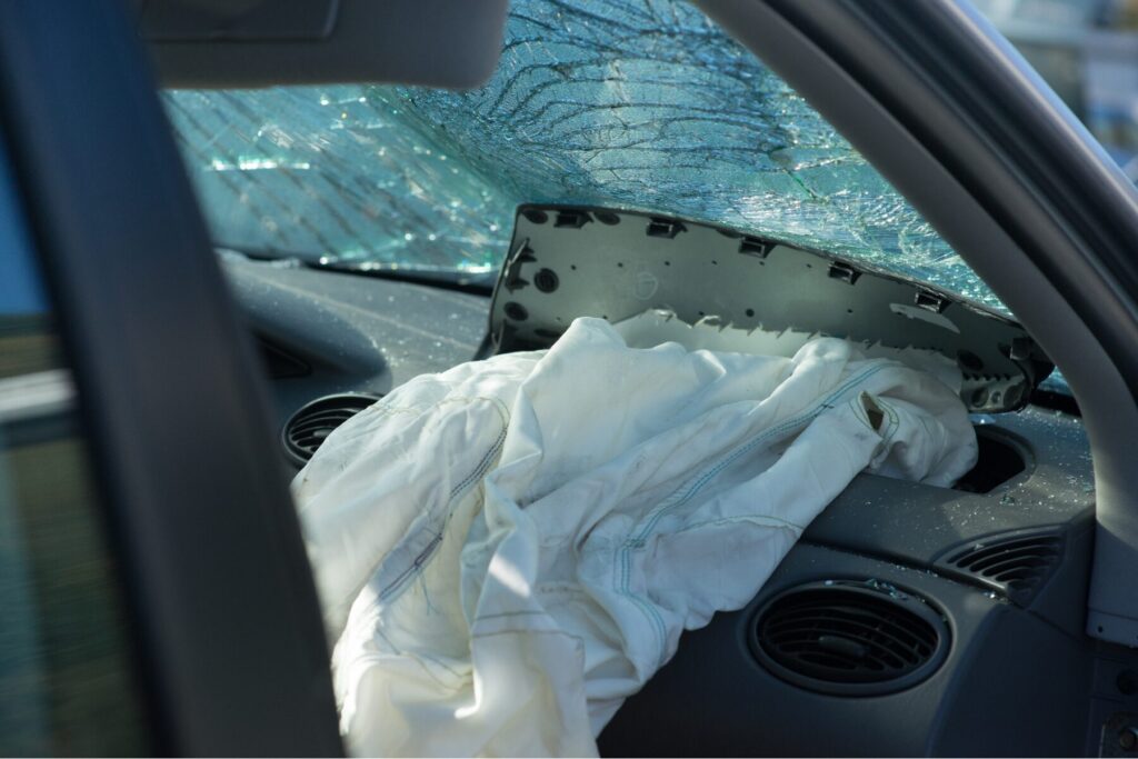Interior of a vehicle after a serious crash showing a deployed airbag and shattered windshield, illustrating the type of collision that often leads to a car accident settlement.