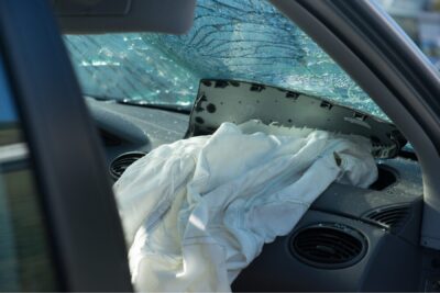Interior of a vehicle after a serious crash showing a deployed airbag and shattered windshield, illustrating the type of collision that often leads to a car accident settlement.