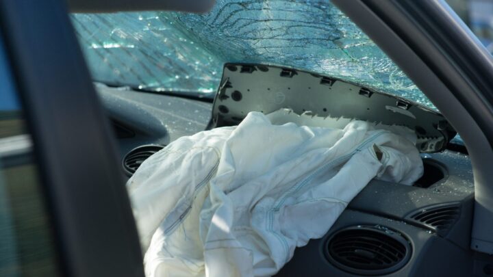 Interior of a vehicle after a serious crash showing a deployed airbag and shattered windshield, illustrating the type of collision that often leads to a car accident settlement.