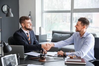 Attorney shaking hands with a client in a law office, representing the value of working with an experienced car accident lawyer when negotiations stall or a car accident lawsuit becomes necessary.