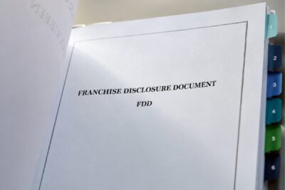 Tabbed franchise disclosure document showing the numbered FDD items an attorney reviews before signing