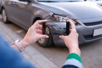 Driver photographing vehicle damage showing what to do after a car accident in Florida