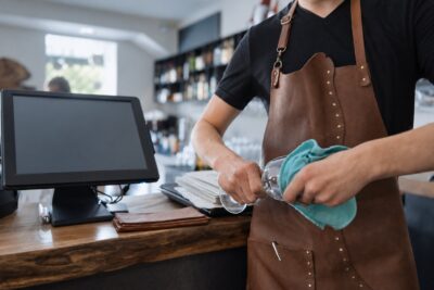 Hospitality employee polishing glassware behind a restaurant counter, illustrating a Florida minimum wage increase