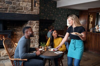 Restaurant server bringing food to customers, representing the tipped cash wage and tip credit in Florida
